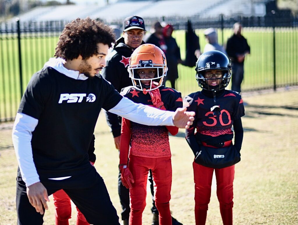 Photo of Elijah Riley coaching young PST student-athlete football players